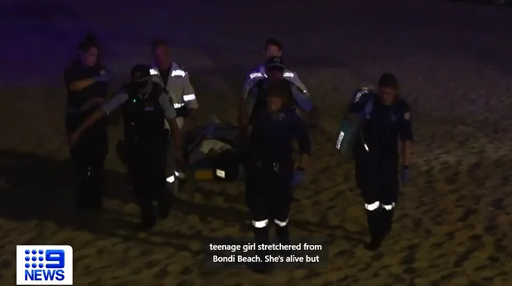Emergency responders carrying a stretcher across Bondi Beach at night in November 2023.