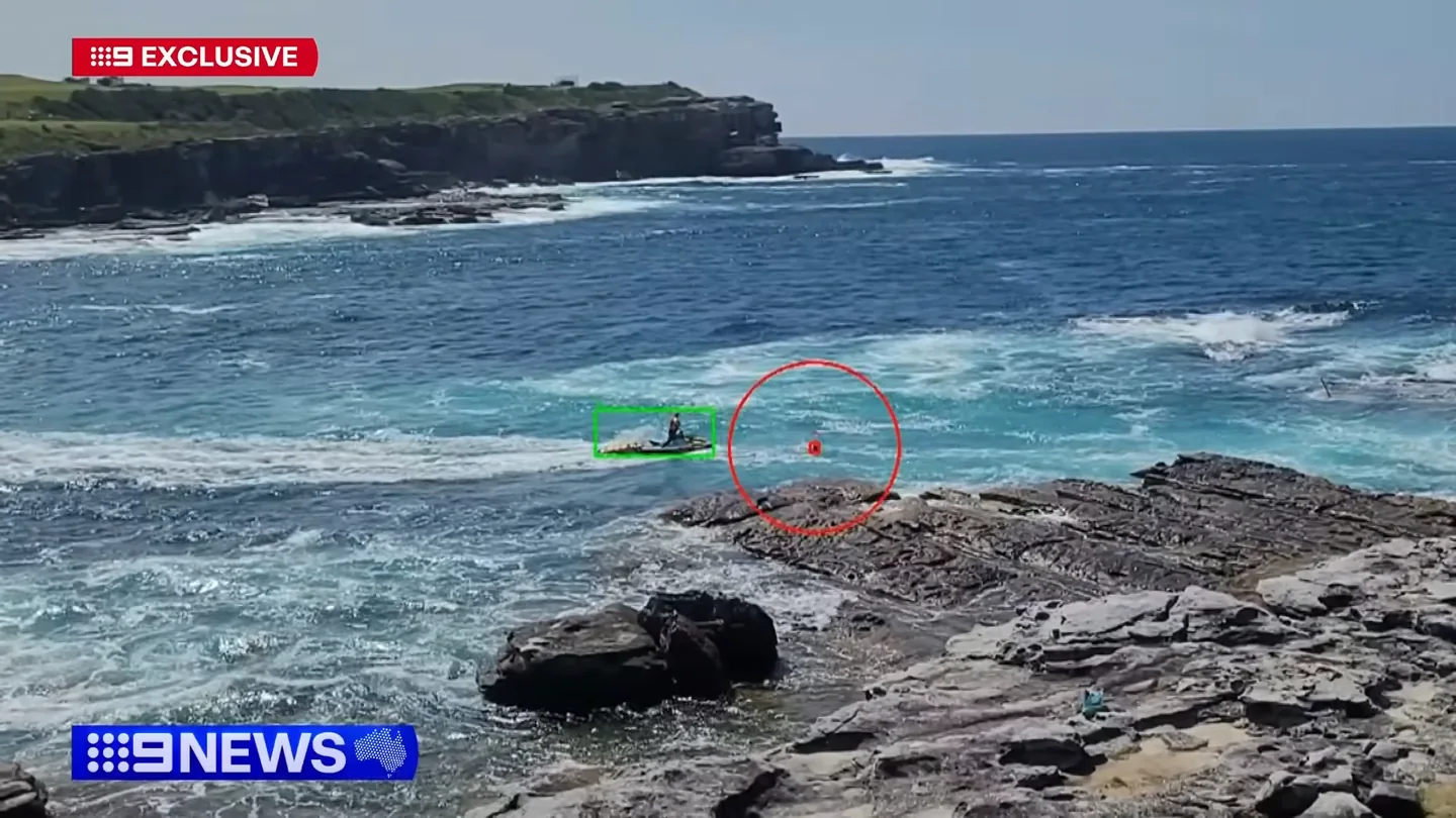 9News still showing a jet ski and a person in the water near the Little Bay rock platform.